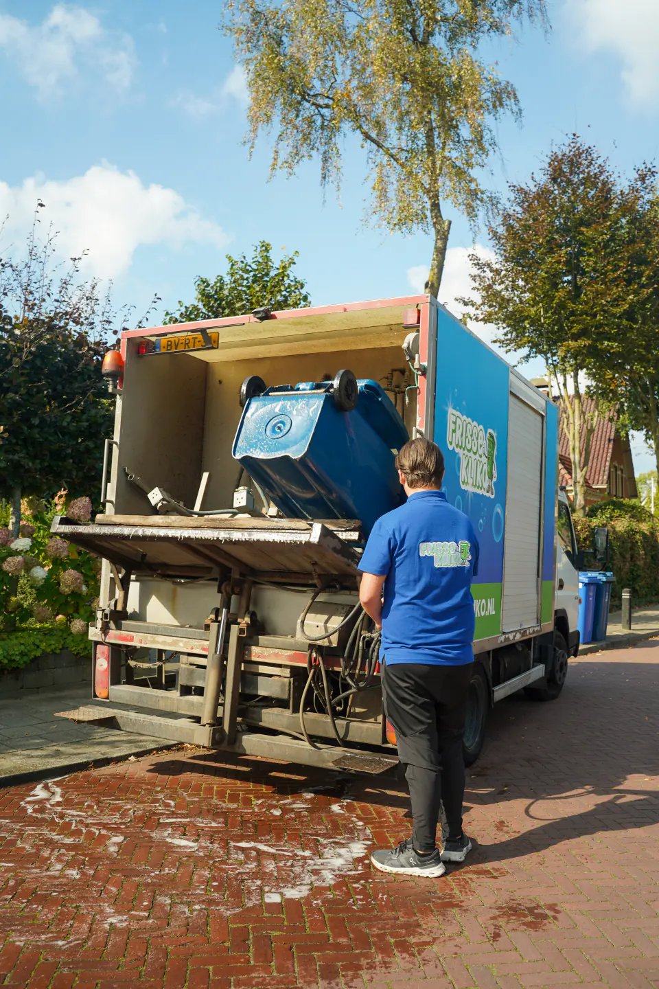 Medewerker brengt een container naar de reinigingswagen van Frisse Kliko.